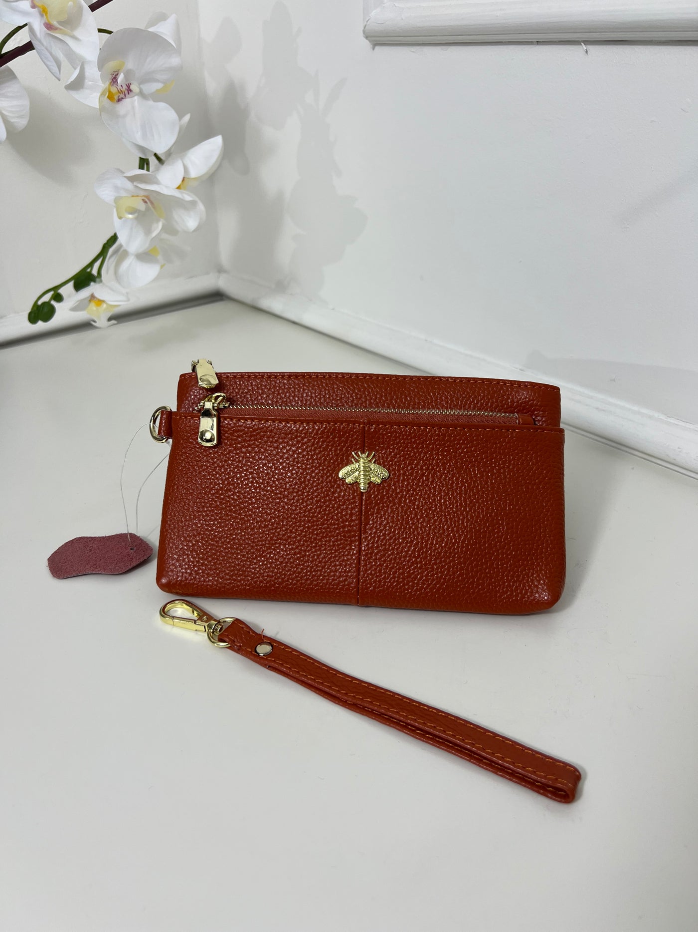 Burnt orange purse with a strap bee detail